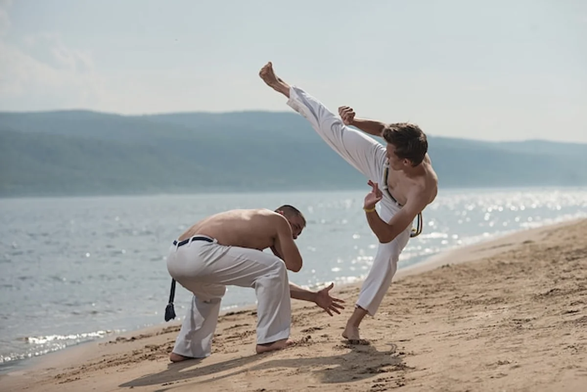 Mężczyźni trenują capoeira na plaży