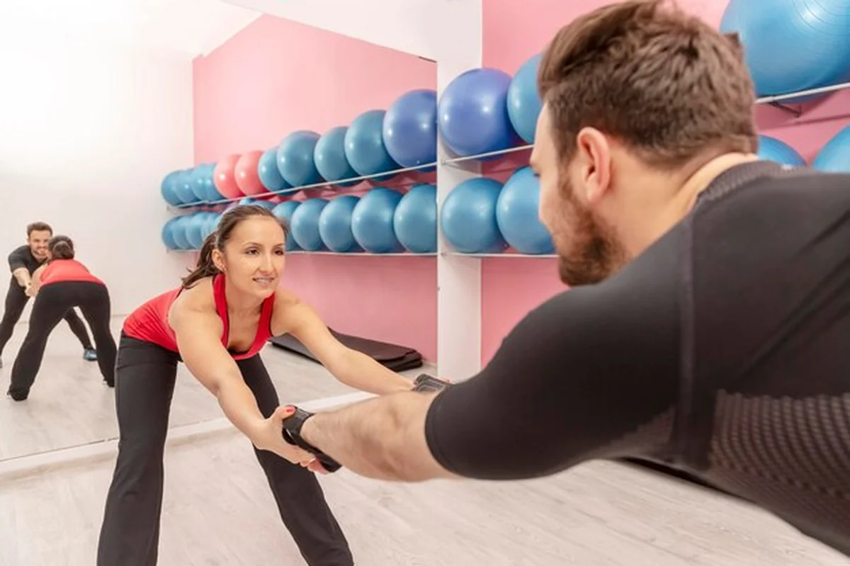 Trener pomagający kobiecie ćwiczyć w siłowni