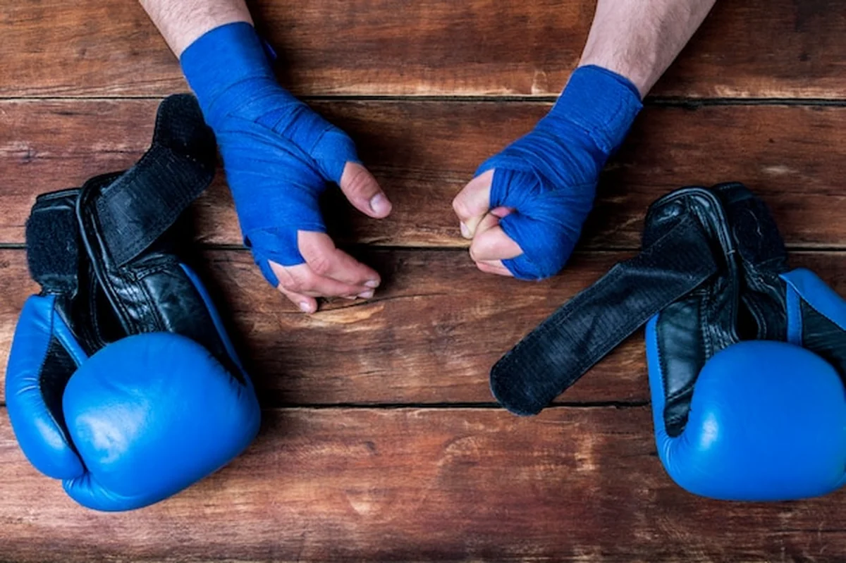 Męskie dłonie w boks bandażach i rękawicach bokserskich na drewnianym tle