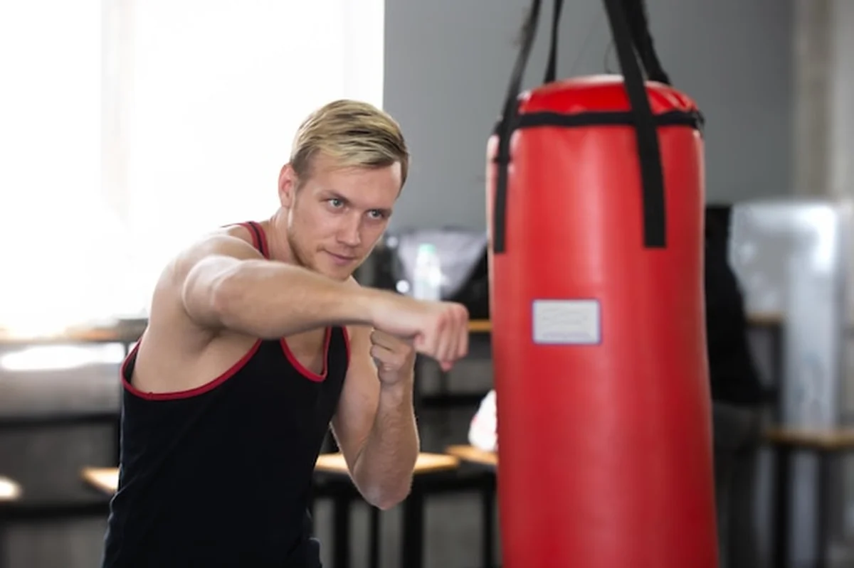 Młody mężczyzna używający worka bokserskiego na siłowni