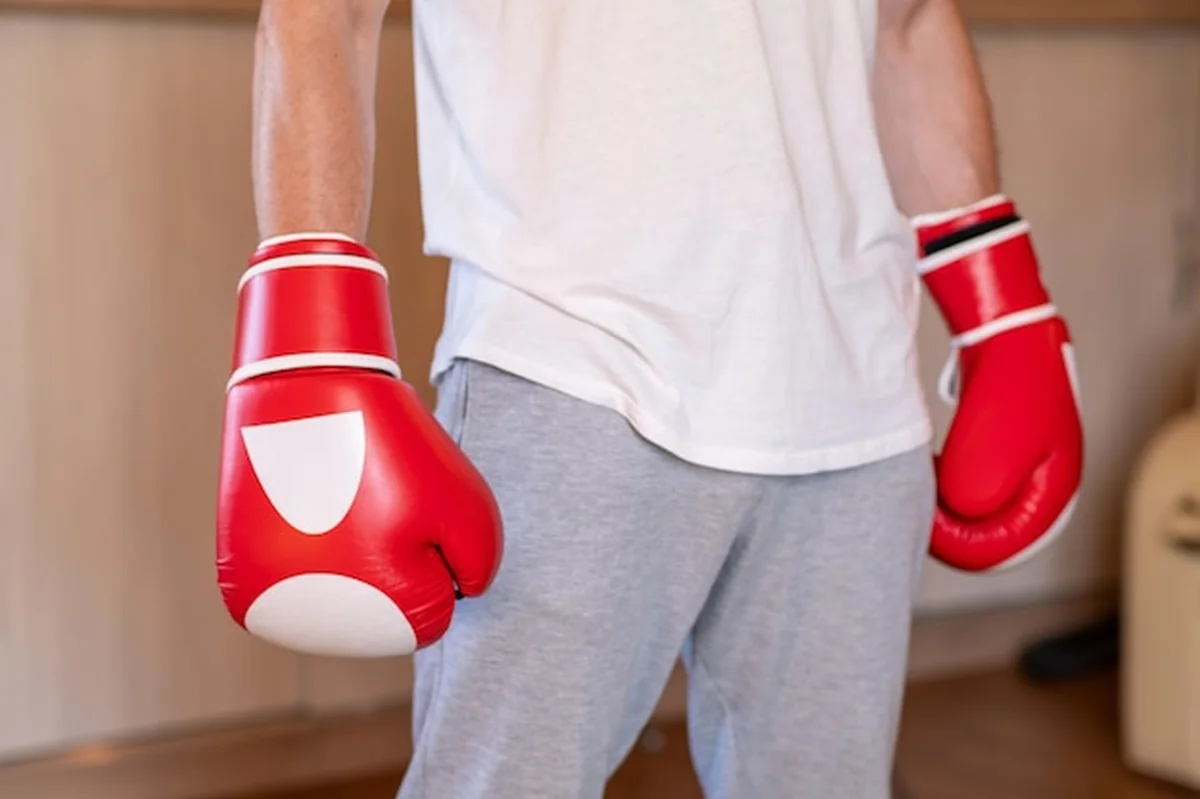 Osoba w białych rękawiczkach bokserskich na siłowni domowej