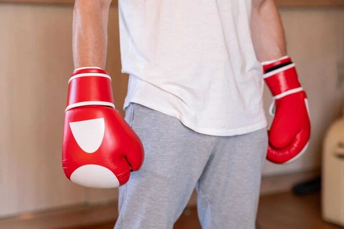 Osoba w czerwono-białych rękawiczkach bokserskich na siłowni domowej
