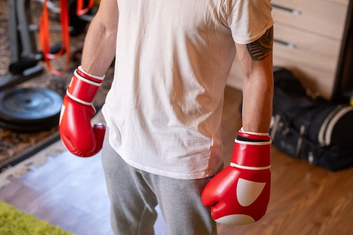 Osoba w czerwono-białych rękawiczkach bokserskich na siłowni domowej