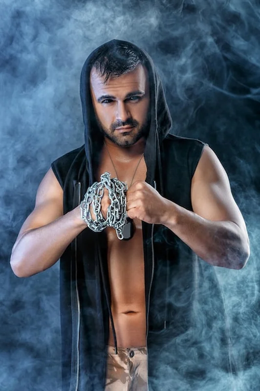 Muskularny mężczyzna z łańcuchem na czarnym tle z dymem